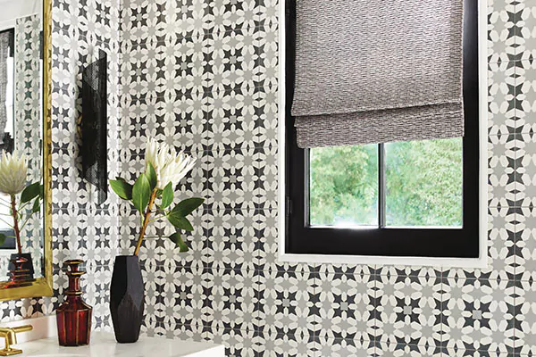 A bathroom with Mediterranean inspired tiles features a Flat Roman Shade made of Tangier Weave in Onyx for added texture