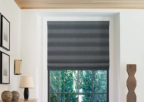 A living room window features a Flat Roman Shade made of Jasmine in Midnight for a contrast to the light off white walls