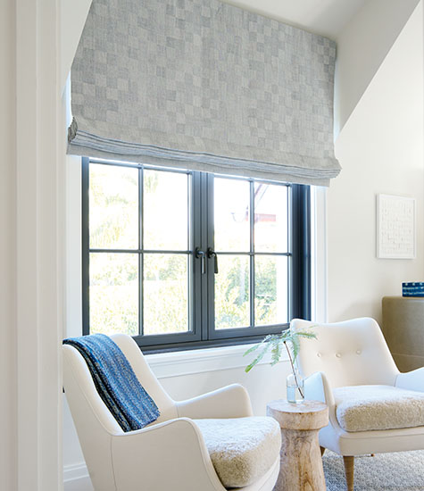 A sitting room features blackout shades for nursery windows made of Flat Roman Shades in Oceana in Slate