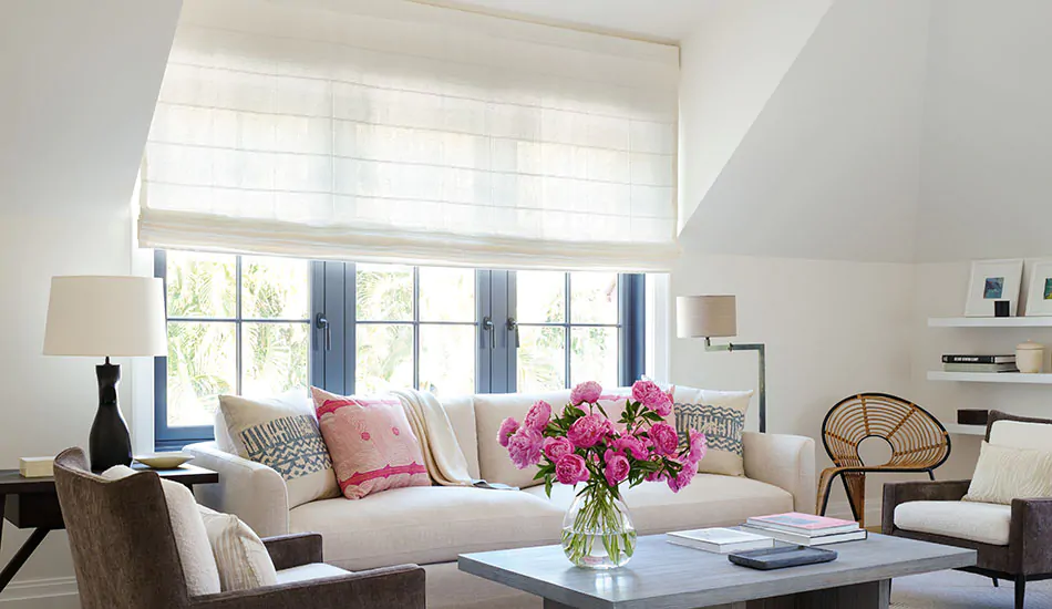 A bright sitting room features outside mount Roman Shades made of Sankaty Stripe in Moon which filters light through it