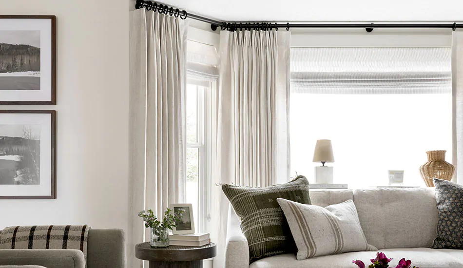 An inviting living room feature studio mcgee window treatments of Flat Roman Shades and complementary Tailored Pleat Drapery