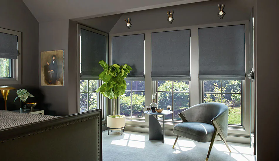 A dark, warm grey bedroom features Flat Roman Shades made of Wool Blend in Charcoal with blackout lining