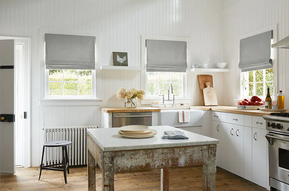 Roman shades for kitchen windows made of Canvas in Stone add a cool grey color to a rustic farmhouse kitchen