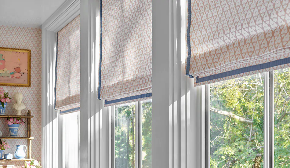Flat Roman Shades with a pink floral design are sunroom window treatments in a sunroom with matching wallpaper
