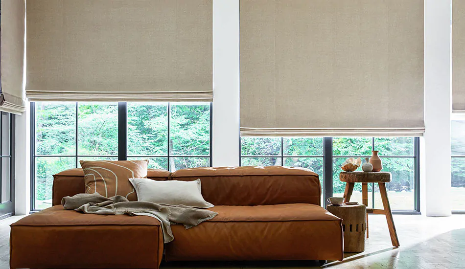 Large floor-to-ceiling windows with flat roman shades offer inspiration for the best type of blinds for living rooms