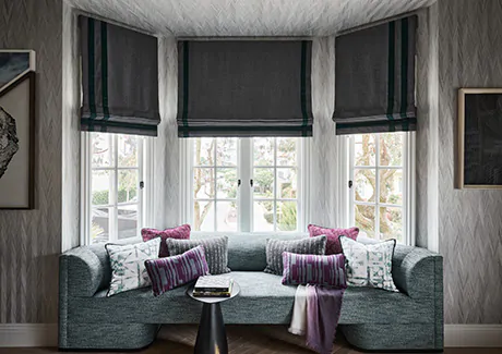 A dark room features flat roman shades made of holland and sherry wool used in place of bay window blinds