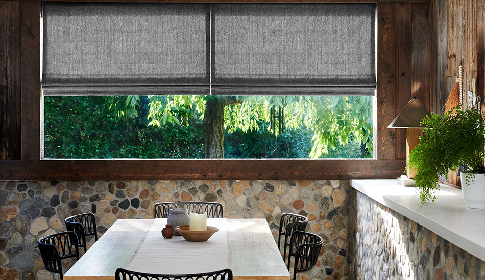 Pull down window shades in the Roman Shade style made of Lowell Tweed in Flint complement stone walls in a dining room