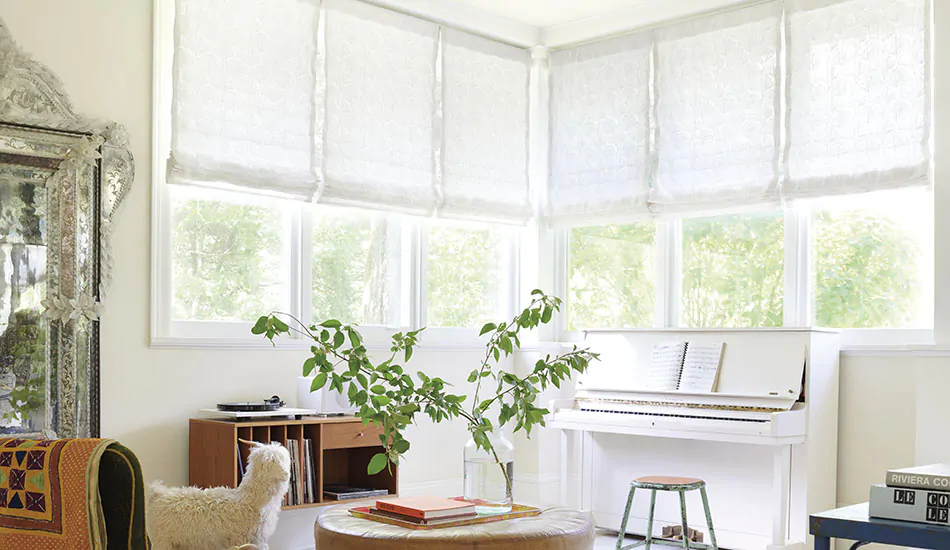 Flat Roman Shades made of Feather Palm Embroidery in Vintage Lace are used as sunroom window treatments in a bright room