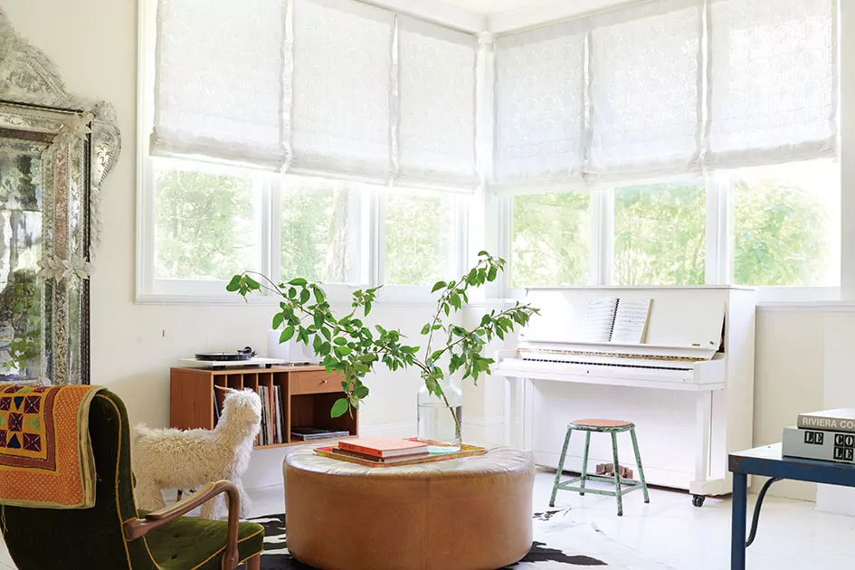 Mid century modern window treatments include white flat roman shades with a subtle leaf pattern in a bright room