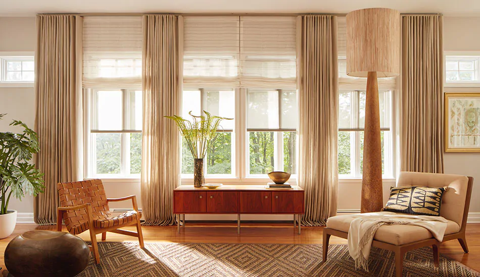 Layered drapery and shades in warm neutral colors add dimension to a living room and exemplify Nathan's window treatment tips