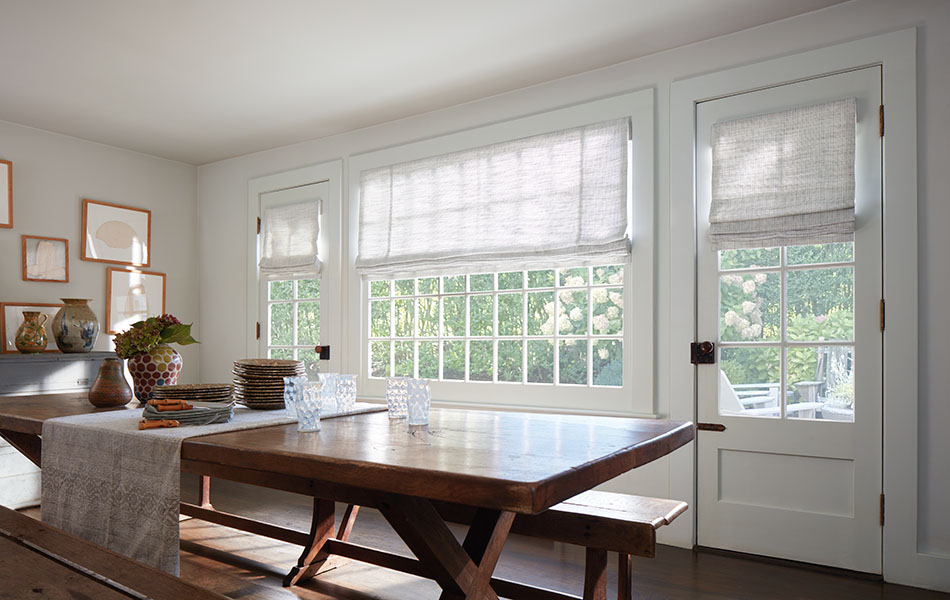 Flat linen Roman Shades made of Shoreline in Cloud deliver idyllic texture to a dining room with a long wood table