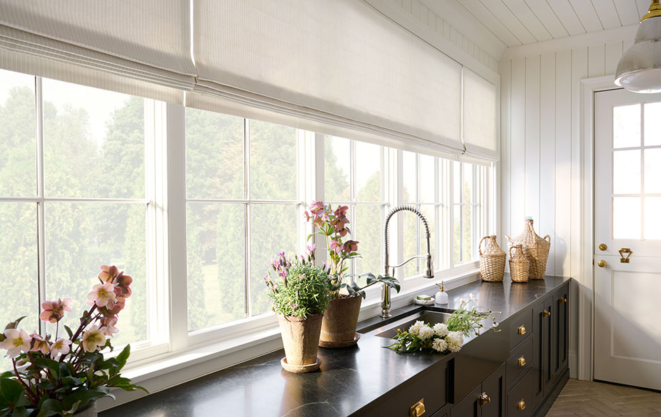 A chic, simple mudroom has Flat Roman Shades made of Ticking Stripe in Dune to contrast the dark cabinets