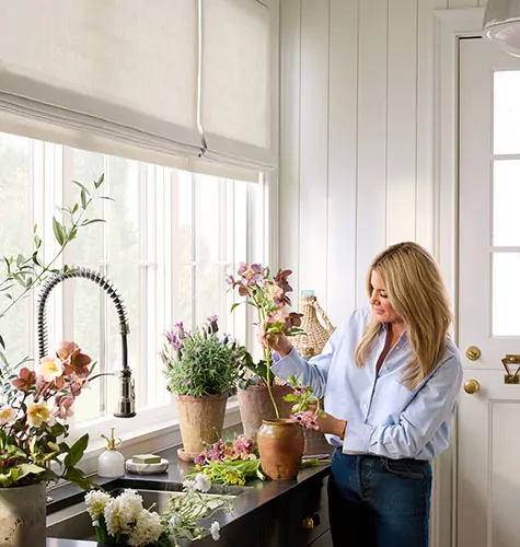 In her mudroom with Flat Roman Shades made of Ticking Stripe in Dune, Shea McGee plants flowers
