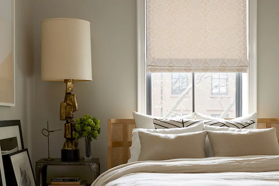 An inviting bedroom features a flat roman shade which is one of the types of window shades or types of shades for windows