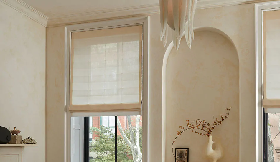 A golden hued bathroom with flat roman shades on a window shows an alternative for how to hang curtains with crown molding