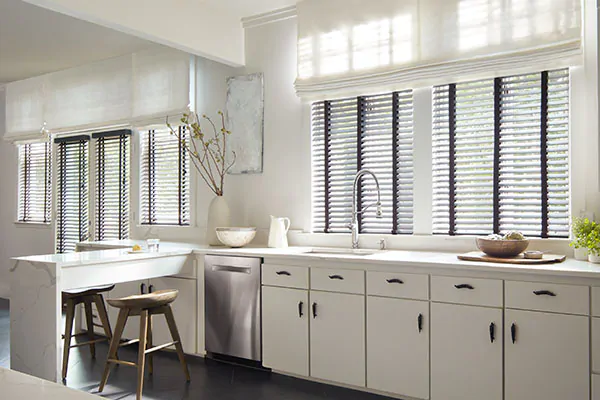 Wood Blinds made of 2-inch Painted Bamboo in Coal contrast the white cabinets and Tangier Weave in Blanco Flat Roman Shades