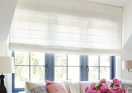 Flat Roman Shades made of Sankaty Stripe in Moon are used as sunroom window treatments on windows behind a white couch
