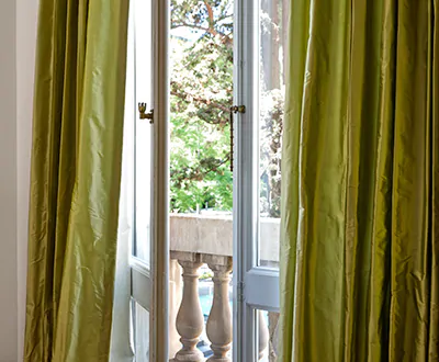 Luxe boho curtains made of Silk Dupioni in Leaf offer a beautiful sheen to a room with old french doors