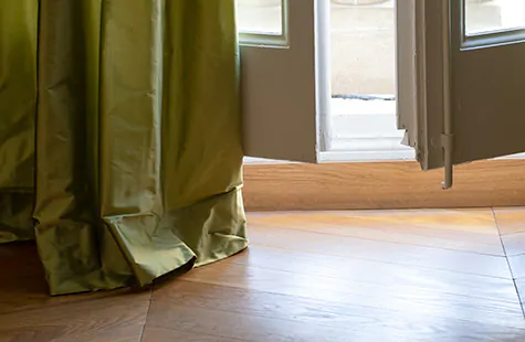 Luxe drapery made from Silk Dupioni in Leaf is puddled on the floor, showing how to install curtain rods to create puddles