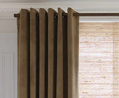 A close up of Grommet Drapery panels made of Velvet in Camel shows the deep, dramatic folds created by the grommets