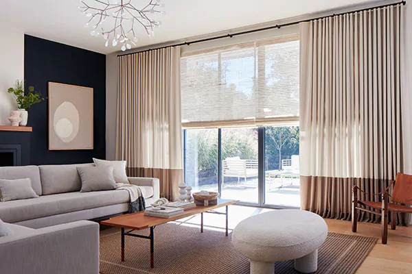 Glass doors in a transitional room have Ripple Fold Drapery in Andes, Caste Wall and Rye, and a woven shade in Cove, Ash