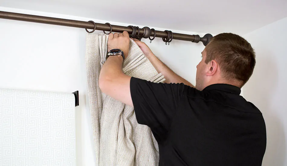 An install professional hooks Pinch Pleat Drapery into curtain rod rings as part of the steps for how to install drapes