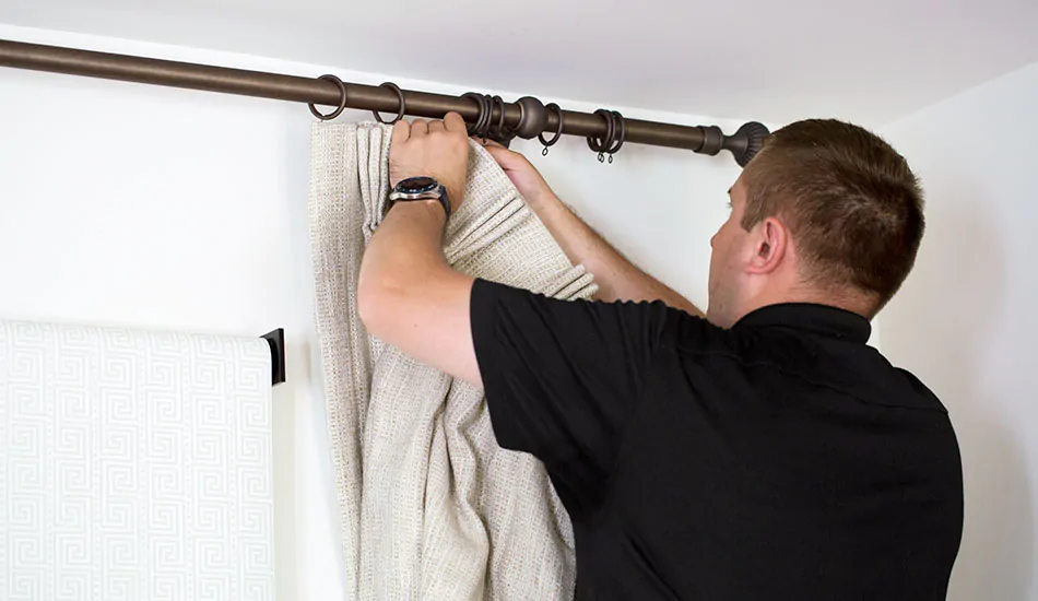 A professional installer shows how to install curtain rods and attach the drapery to the rings in a rod and ring system