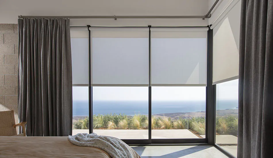 A casual bedroom with a beautiful beach view features corner window curtains made of Herringbone in Onyx