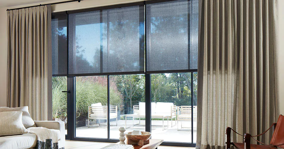 Inverted pleat drapery in a warm greige color on floor-to-ceiling sliding glass doors shows a type of drapery pleat styles