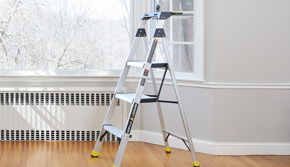 A step ladder sits in front of a bay window in preparation for the first step of how to measure for curtains: gathering tools