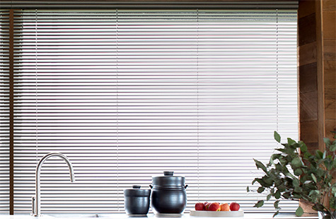 Types of blinds include Metal Blinds made of 1-inch Metal in Silver on a window over counter with black jars and apples