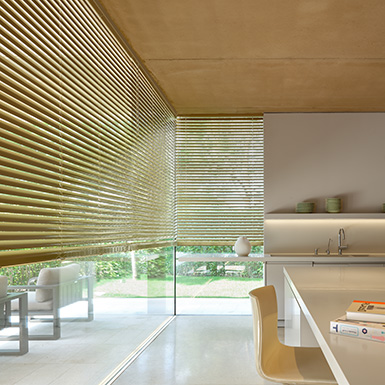 A modern kitchen features metal blinds for tall windows made from 2-inch aluminum in golden Champagne