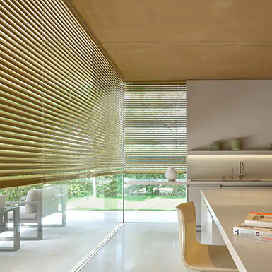 A modern kitchen features metal blinds for tall windows made from 2-inch aluminum in golden Champagne