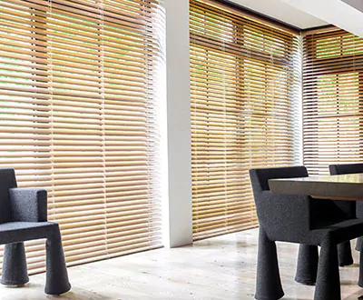 A dining room with tall windows and doors feature Metal Blinds made of 2-inch Champagne for a modern look