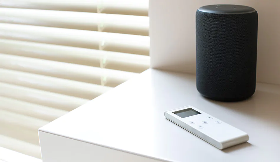 A motorization remote and smart home device sit on a table next to Blinds showing how to put blinds down with motorization