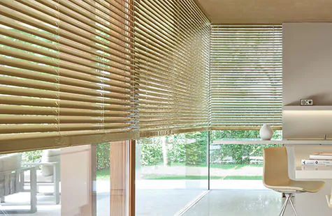 Metal Blinds made of 2-inch Champagne covers tall wide windows in a modern kitchen with warm golden tones