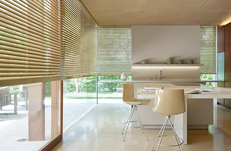 A bright, warm kitchen with tall windows has Metal Blinds made of Champagne giving the space an inviting golden hue