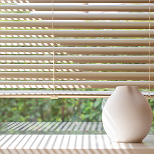A bright window with a simple shelf and essential oil diffuser is covered by Metal Blinds made of 2-inch Metal in Champagne