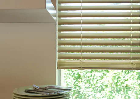 Small window blinds made of Metal in Champagne lend a modern metallic look to a window above a kitchen counter