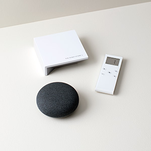 The Shade Store motorization remote and wireless link sit on a white table next to a smart home device