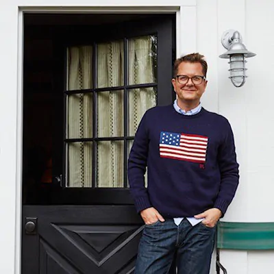 Nathan Turner wears a navy blue sweatshirt with the American Flag on it while standing in front of a black exterior door