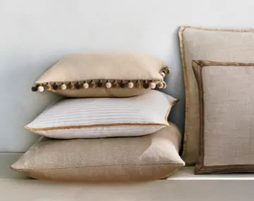 Multiple Square Pillows stacked against a white wall featuring various styles in neutral colors