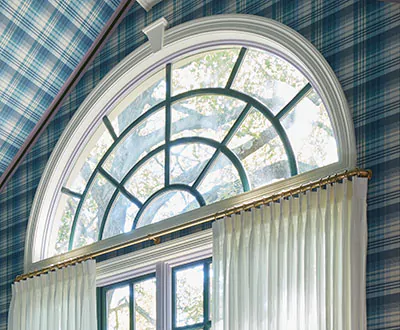 A beautiful half-circle arch has curtains for arched windows made of Pinch Pleat Drapery in C.O.M. hanging below the arch