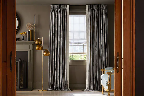 An elegant living room features Pinch Pleat Drapery made of Silk Dupioni in Pewter with interlining for a full luxe look