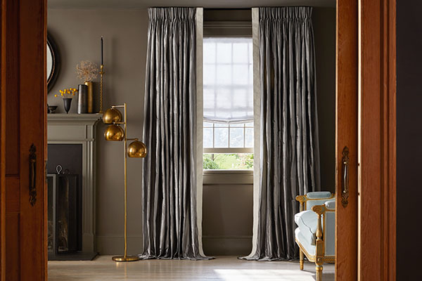 An elegant, traditional living room features silk curtains made of Pinch Pleat Drapery in Silk Dupioni, Pewter