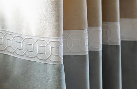 A close up of velvet curtains made of Velvet in Cream and Silver shows the Samuel & Sons Sakiori Embroidered Trim in Mist