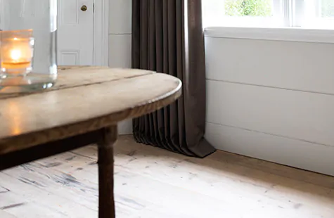 A kitchen featuring dark gray curtains that kiss the warm wood floor shows how to hang curtains with a break length