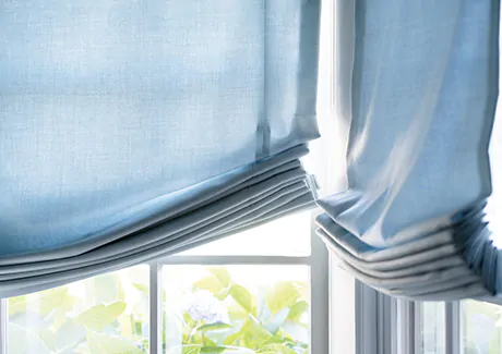 A close up of coastal window treatments of Relaxed Roman Shades made of Andes in Fountain shows the soft swoop of fabric