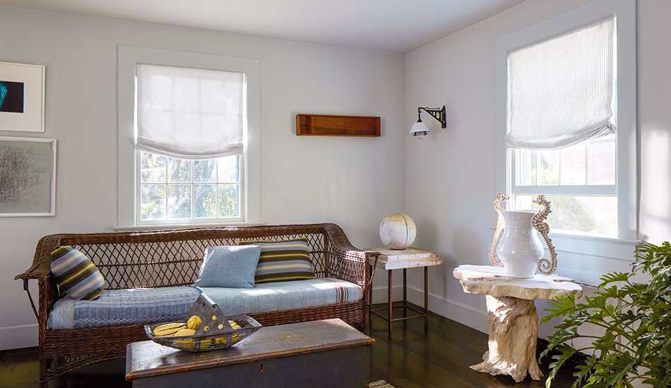 A coastal inspired sitting room features Relaxed Roman Shades in Windsor Stripe in Sage for a subtle pinstripe design