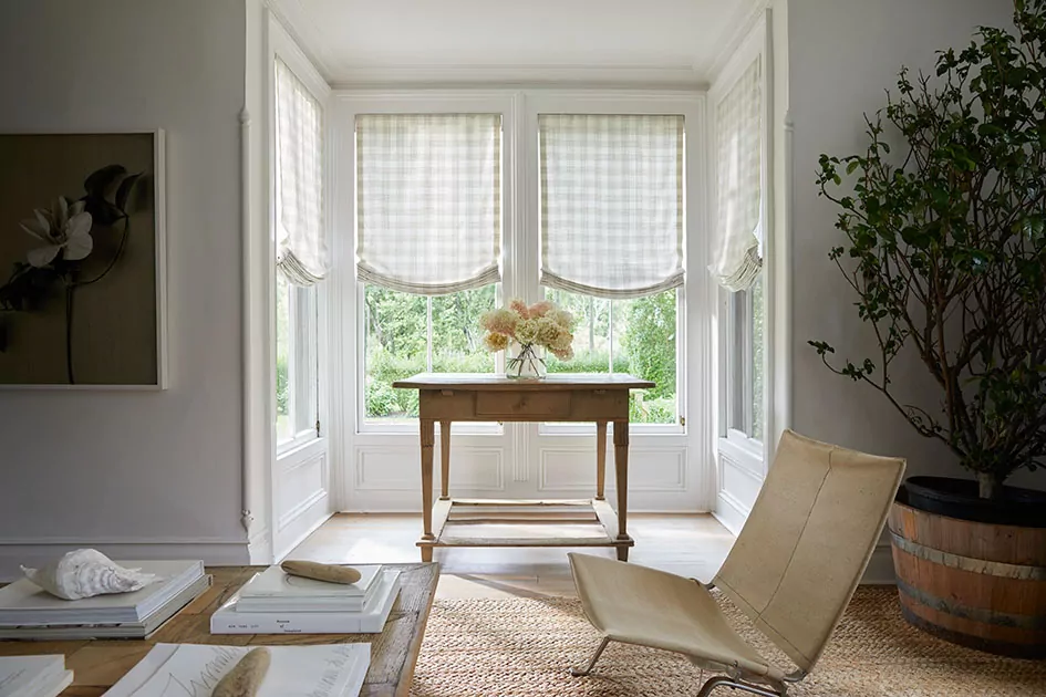 A breakfast nook features relaxed roman shades one of the types of window shades with a checkered pattern